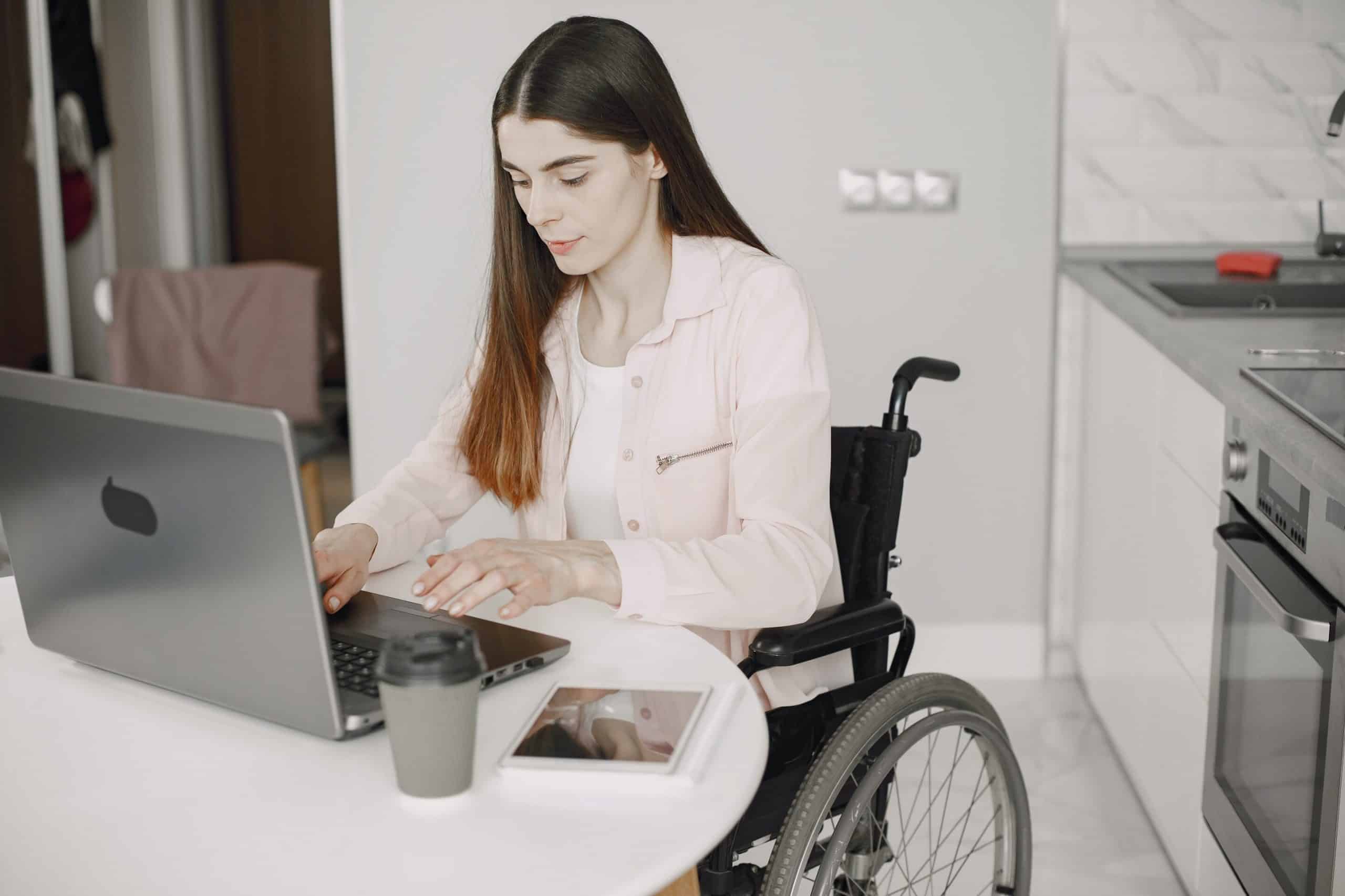Lady sat in her wheelchair with a laptop in front of her, she is in a spina bifida counselling session