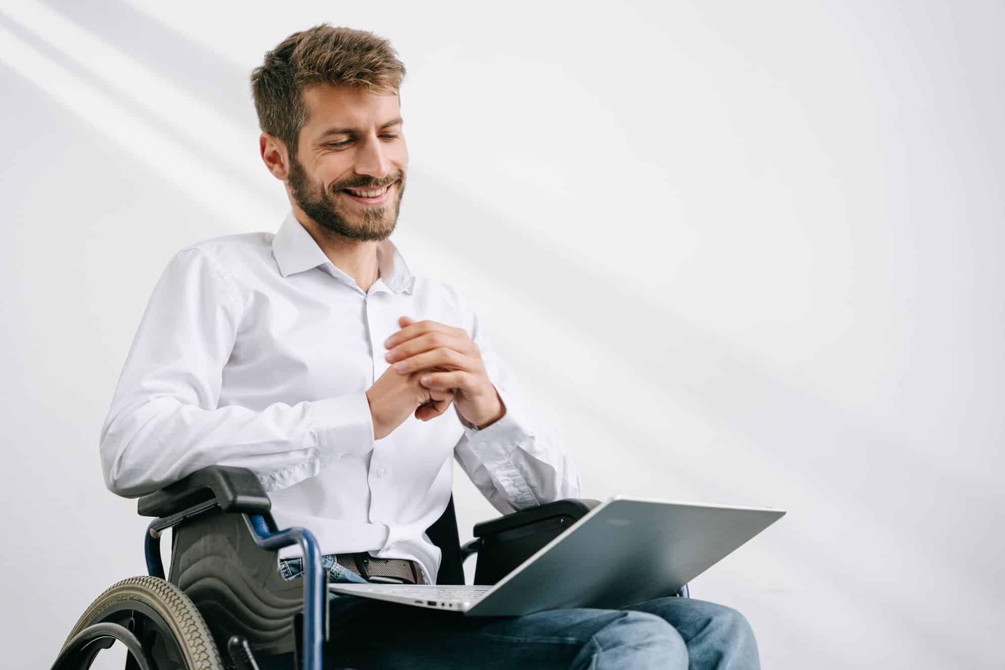 Man sat in a wheelchair looking at his laptop. He is taking a cerebral palsy counselling session
