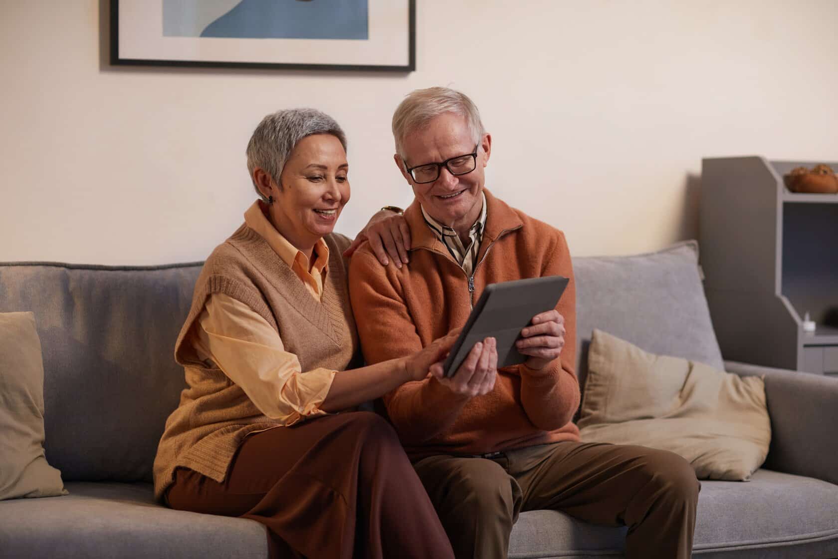 a couple sat on a sofa looking into a Ipad, they are in a Parkinson's Disease counselling session