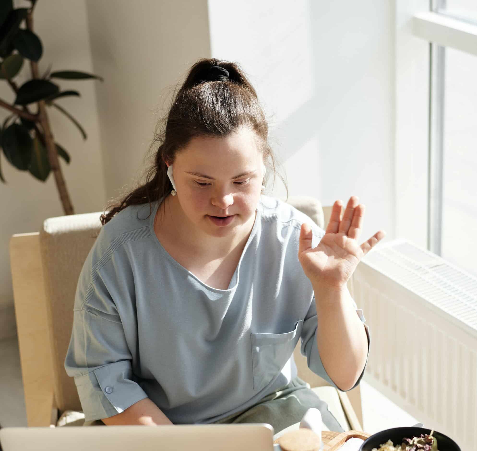 A lady sat on on a chair saying high. She is in Down's Syndrome Counselling Session