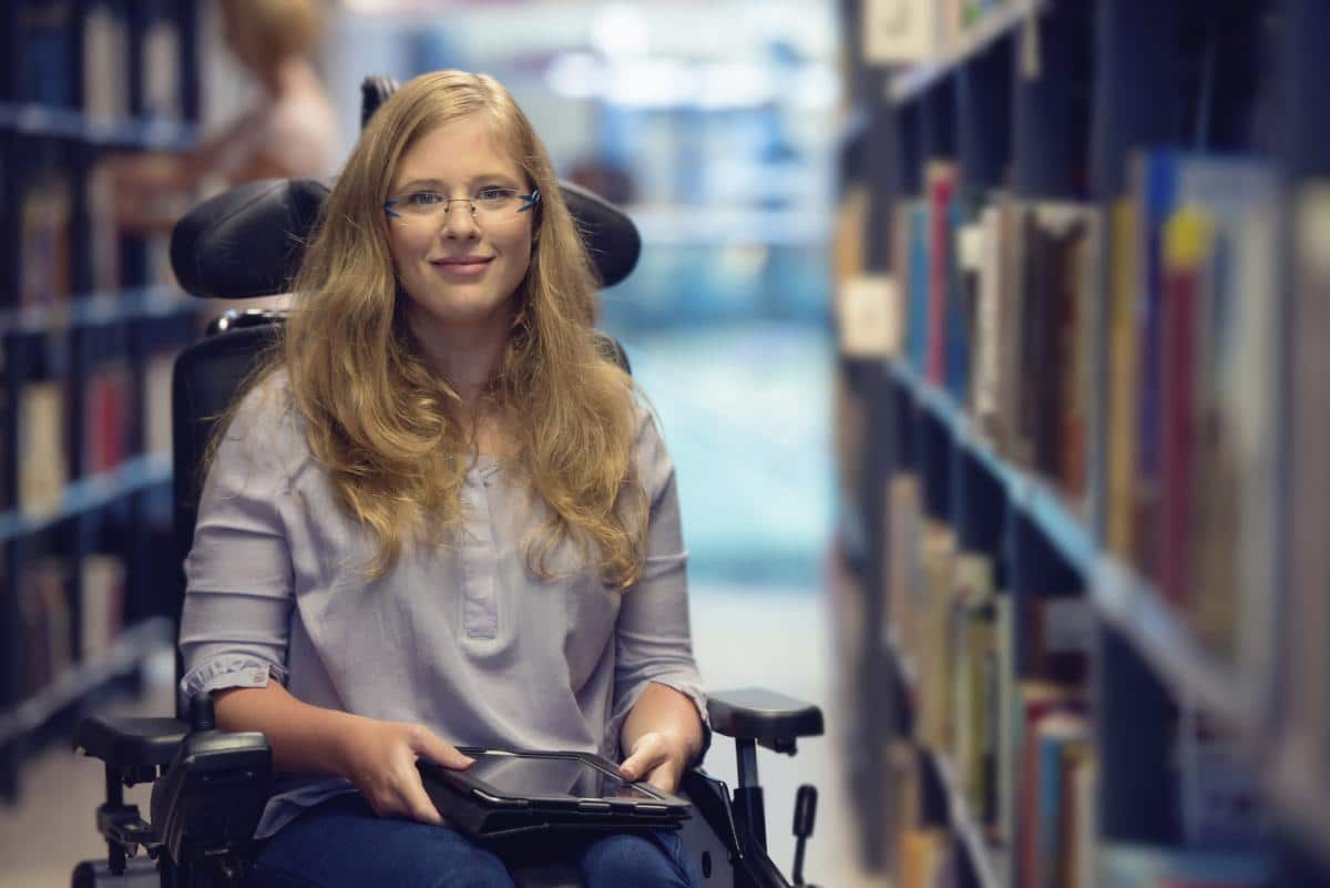 Lady in a wheelchair, she is being hugged by a family member. The lady in the wheelchair is explaing how much her Parkinson's Disease counselling is helping her.