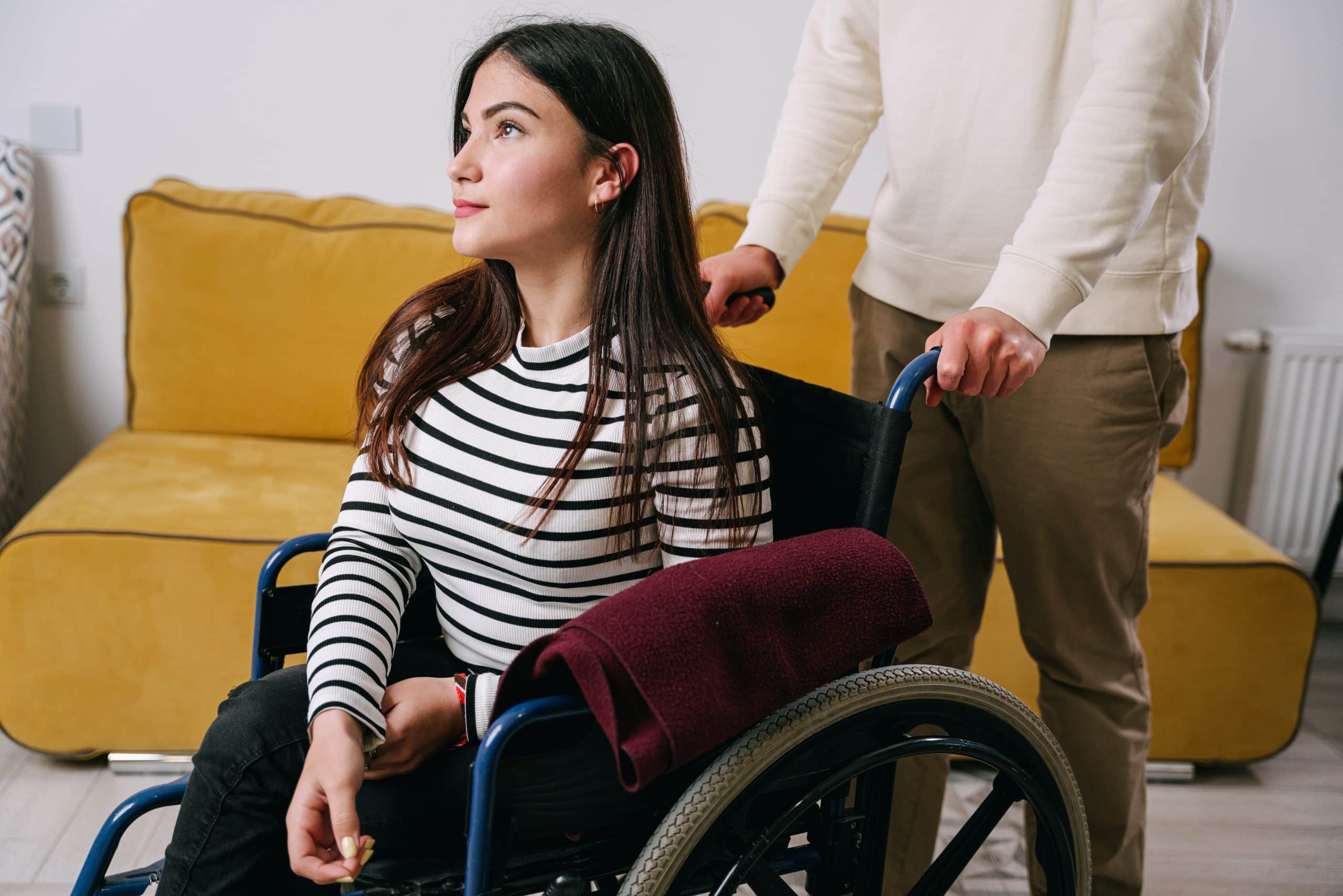 A man sat in his wheelchair in a park. He is sat with his partner and they are talking about spinal cord injury counselling