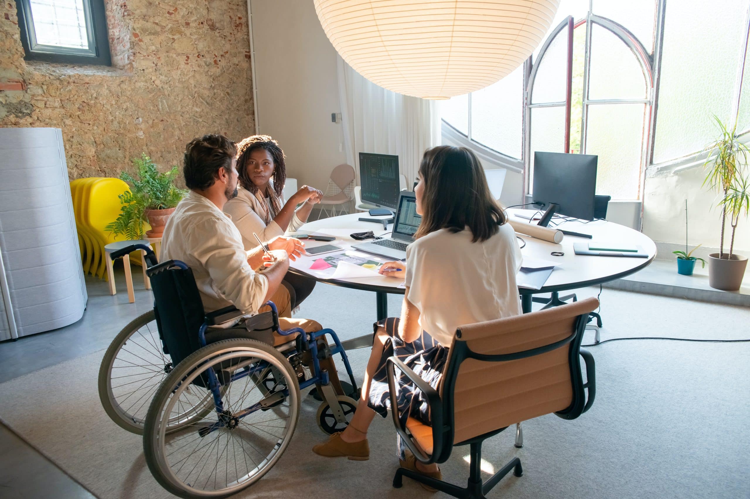 Lady with a red jacket, she is in a wheelchair looking forwards with a warm smile. She has her laptop, she is about to start a disability counselling session.