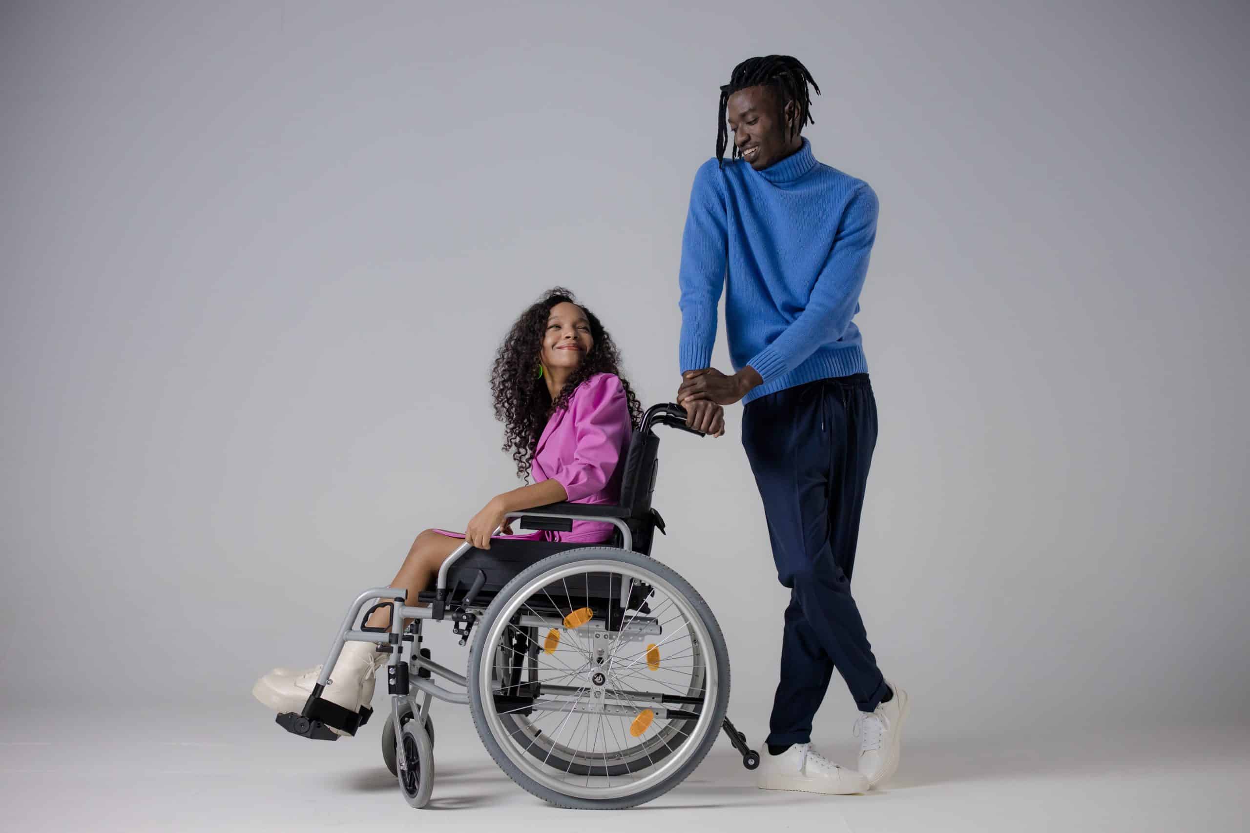 A man sat in his wheelchair in a park. He is sat with his partner and they are talking about spinal cord injury counselling